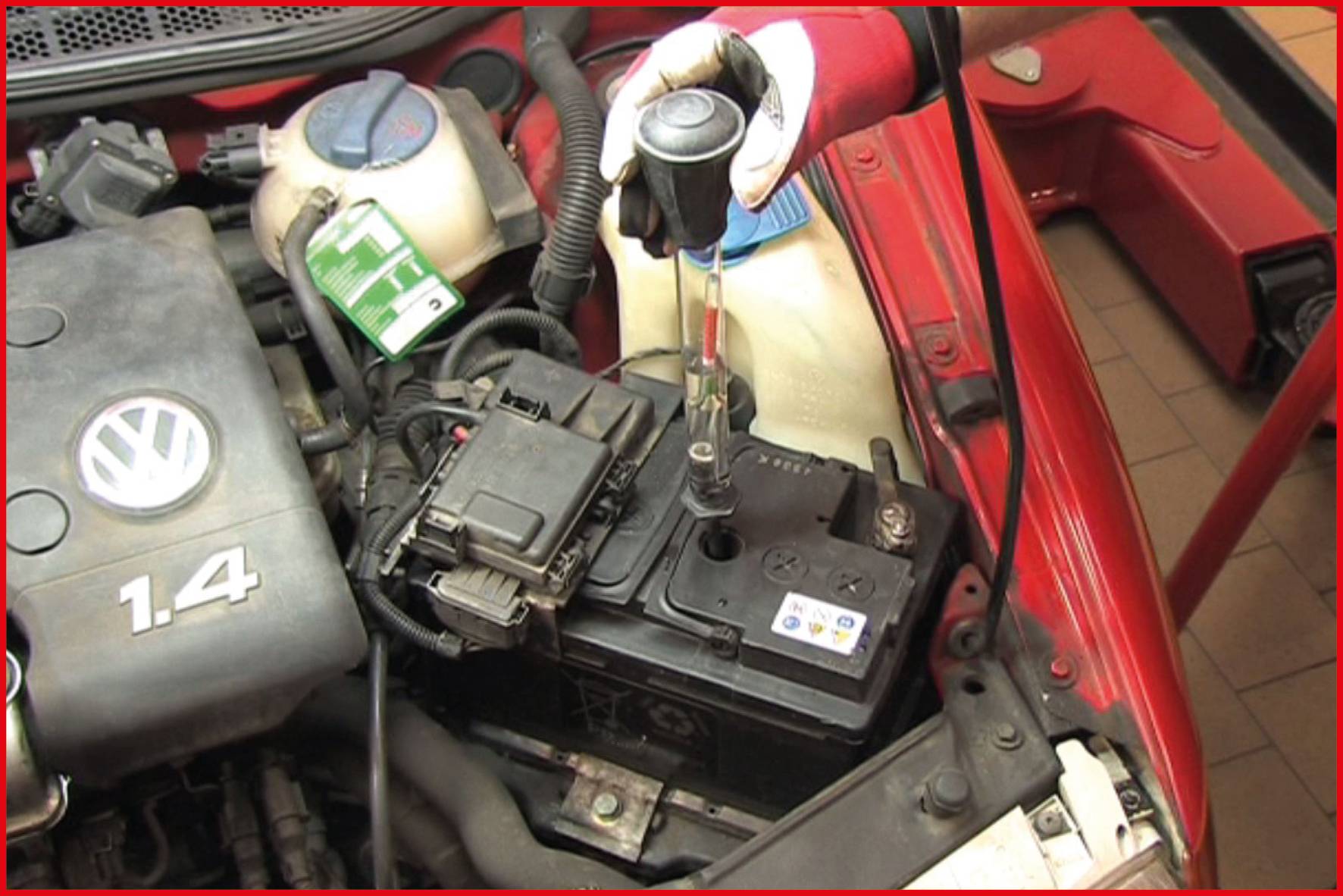 'Ein Mechaniker überprüft die Batterie eines Autos mit einer Voltprüfung. Die Motorhaube ist geöffnet, ein Messgerät ist angeschlossen.'