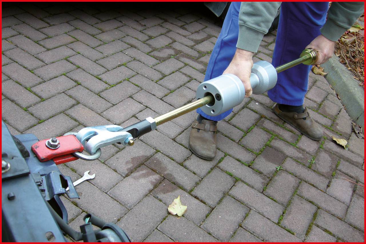Person legt ein Werkzeug auf einen Anhänger bei einer Metallverbindung an. Verwendung von Hebelarm zur Sicherung.