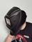 Eine Person trägt einen schwarzen Schweißhelm. Das Visier ist leicht rosa getönt. Die Person trägt ein schwarzes T-Shirt mit Markenlogos.