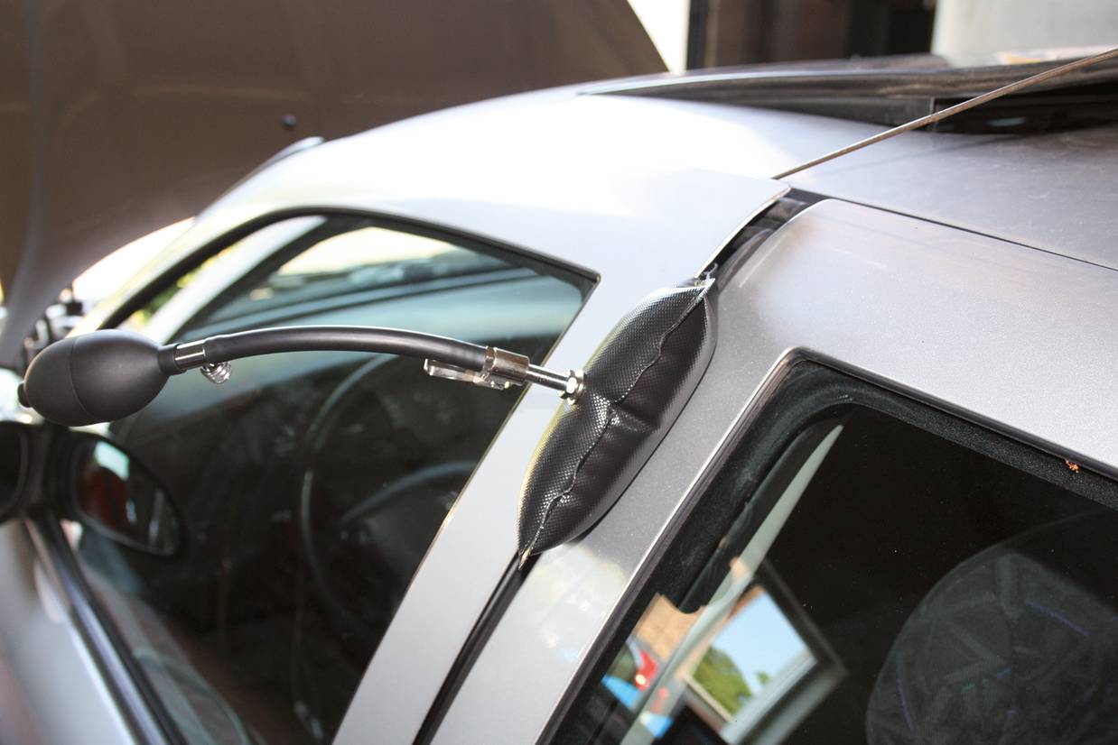 Ein Luftkissenkeil ist zwischen Tür und Rahmen eines Autos eingesetzt, um die Tür vorsichtig zu öffnen, ohne sie zu beschädigen.