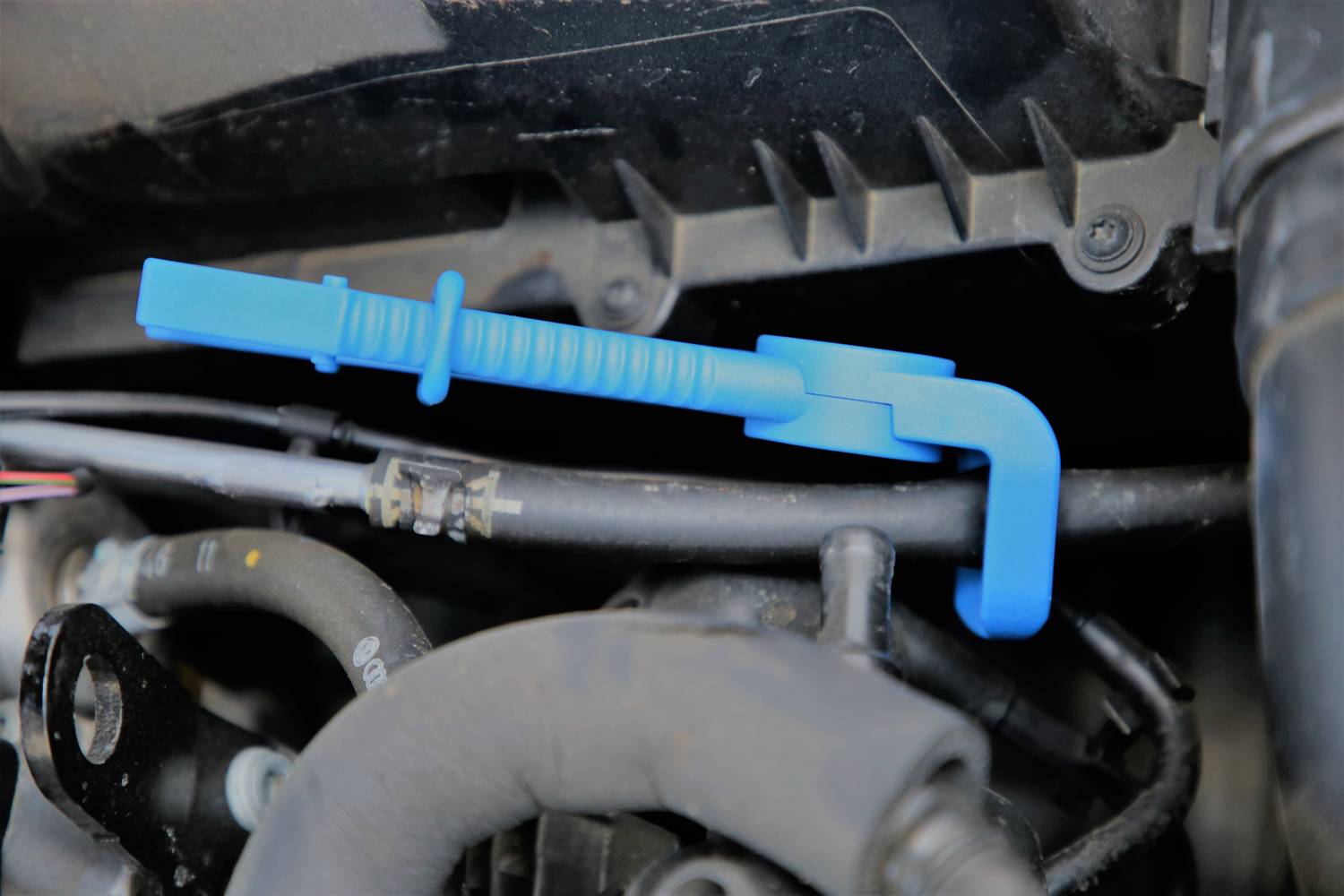 Blauer Automotor-Schlauchclip hält Schläuche in einem Motorraum zusammen.