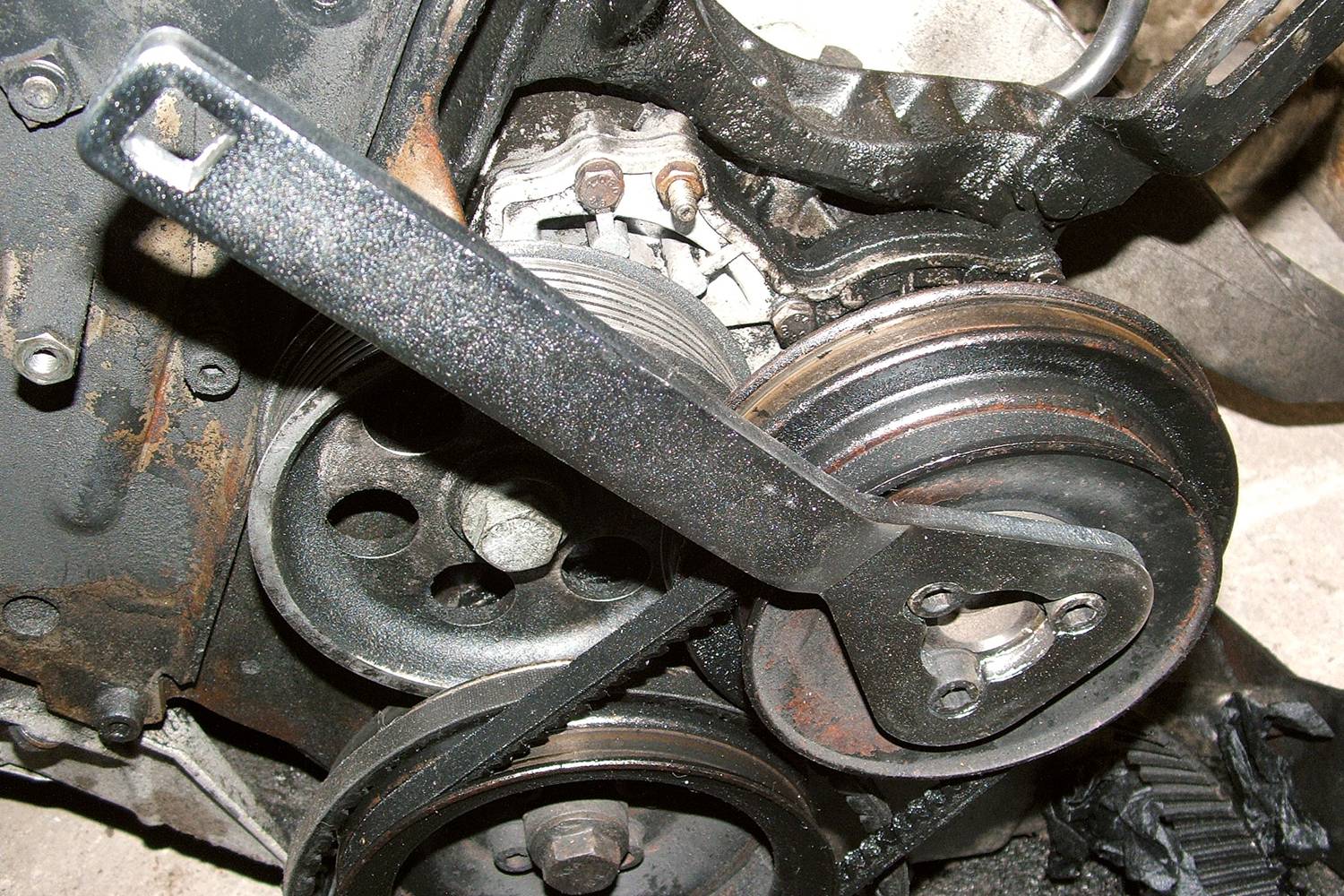 Ein Schraubenschlüssel greift in eine rostige Riemenscheibe eines Motors ein, zeigt eine Reparaturszene mit Werkzeug.