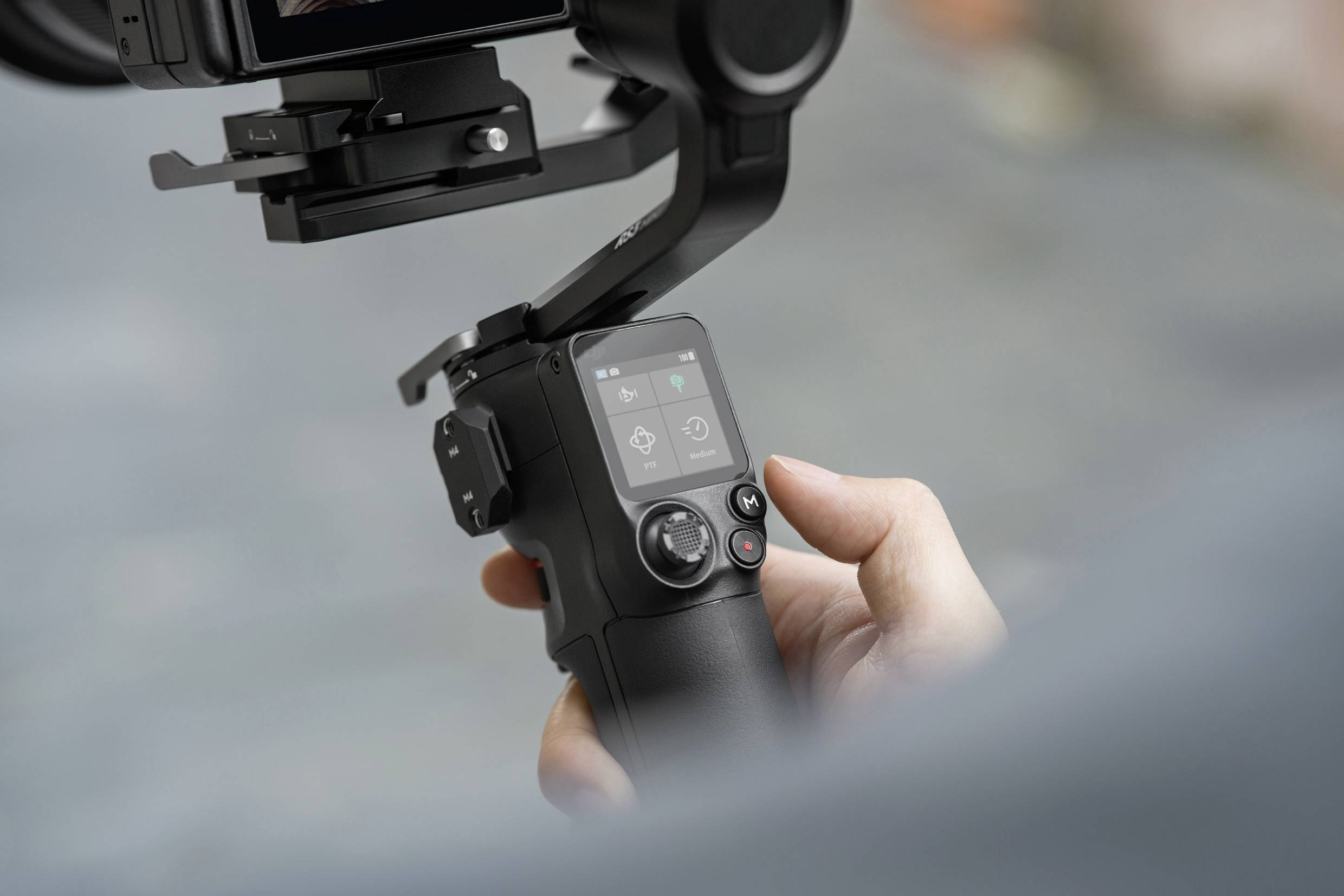 Eine Hand hält einen Kamerastabilisator mit Display, der eine Kamera stabilisiert.