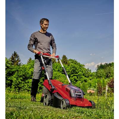 Ein Mann mäht bei sonnigem Wetter mit einem roten Rasenmäher das Gras in einem grünen Garten. Im Hintergrund sind Bäume sichtbar.