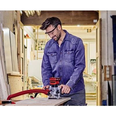 Ein Mann trägt Schutzbrille und bedient eine Tischfräse in einer Werkstatt. Er konzentriert sich auf die Holzbearbeitung.