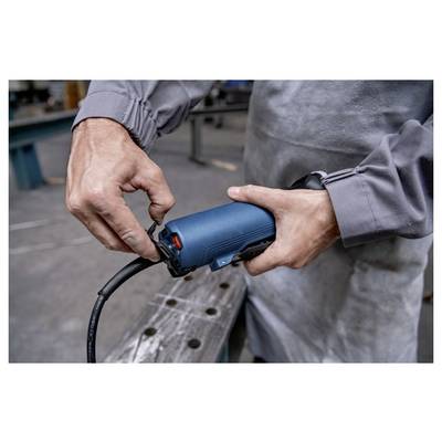 Eine Person in Arbeitskleidung benutzt ein blaues Elektrowerkzeug in einer Werkstatt und konzentriert sich darauf, Einstellungen vorzunehmen oder eine Komponente anzubringen.