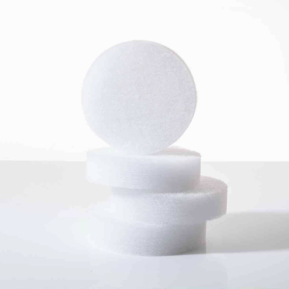Weiße, kreisförmige Filzstücke in unterschiedlichen Stapelhöhen auf weißem Hintergrund. Minimalistisches Stillleben.