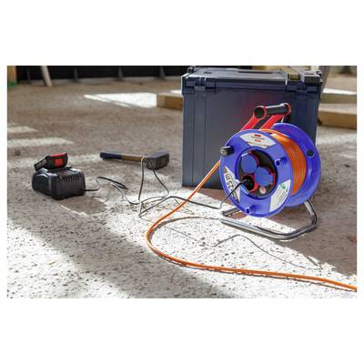 Tragbare Kabeltrommel mit orangem Kabel, Ladegerät und Werkzeugkasten auf einem Betonfußboden auf einer Baustelle.
