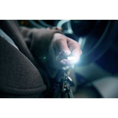 Eine Person hält einen beleuchteten Autoschlüssel in der Hand, während sie im Auto sitzt.