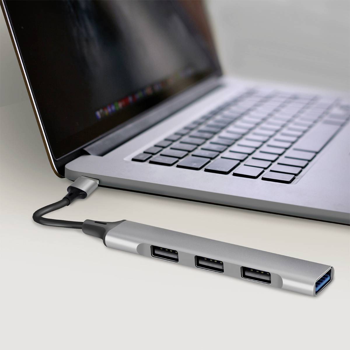 Ein Laptop ist mit einem USB-C-Hub verbunden, der drei USB-Anschlüsse bereitstellt. Der Hub erweitert die Anschlussmöglichkeiten des Laptops.
