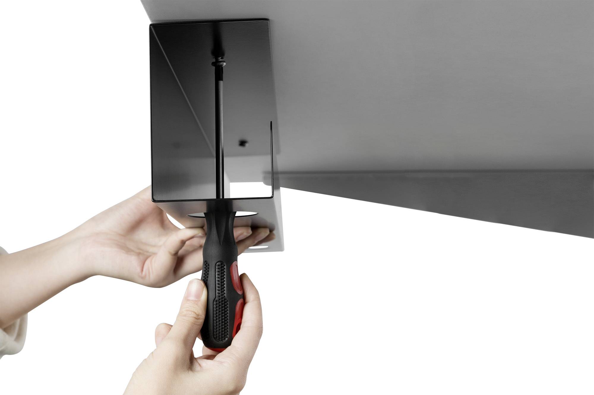 Person befestigt eine schwarze Halterung unter einer Oberfläche mit einem Schraubendreher.