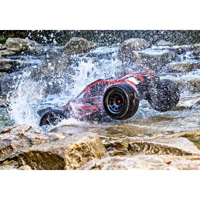Ein ferngesteuertes Auto im Sprung über einen Wasserlauf, spritzendes Wasser umgibt es. Dynamische Action in einer natürlichen Umgebung.