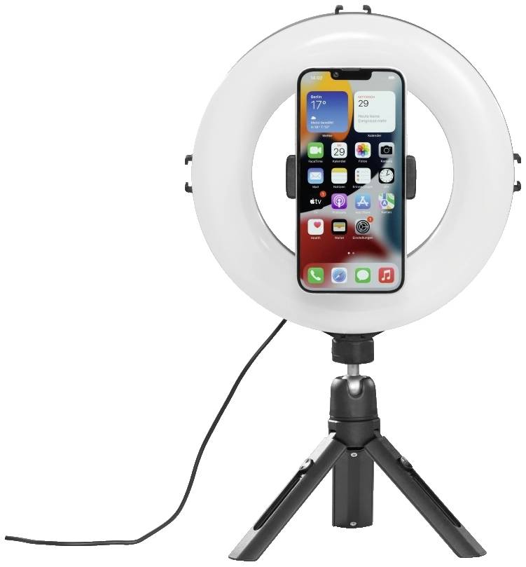 Ein Smartphone ist in einem weißen Ringlicht auf einem dreibeinigen Stativ befestigt, das für Videoaufnahmen oder Selfies genutzt wird.
