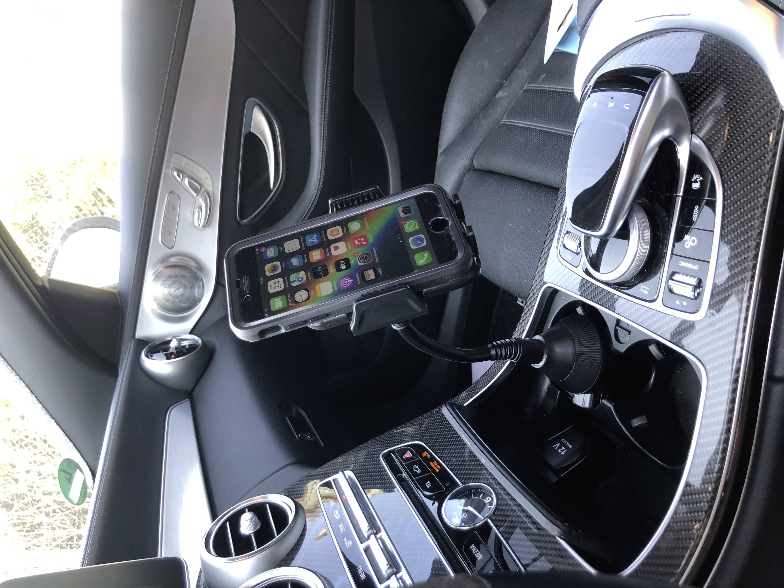 Ein Smartphone ist in einer Halterung im Auto befestigt, sichtbar mit mehreren App-Symbolen auf dem Bildschirm.