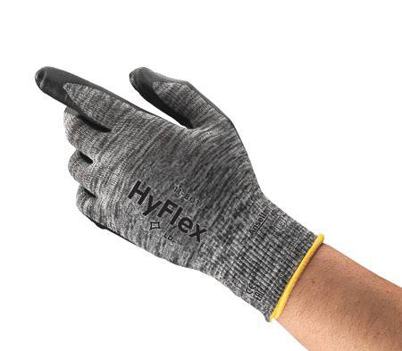 Eine grau-schwarze HyFlex-Schutzhandschuh an einer Hand mit einer gelben Manschette, geeignet für präzise Arbeiten und Schutz.