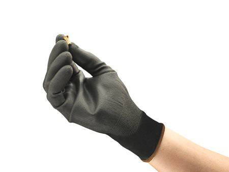 Eine Hand mit schwarzem Handschuh hält ein kleines Metallelement zwischen den Fingern.
