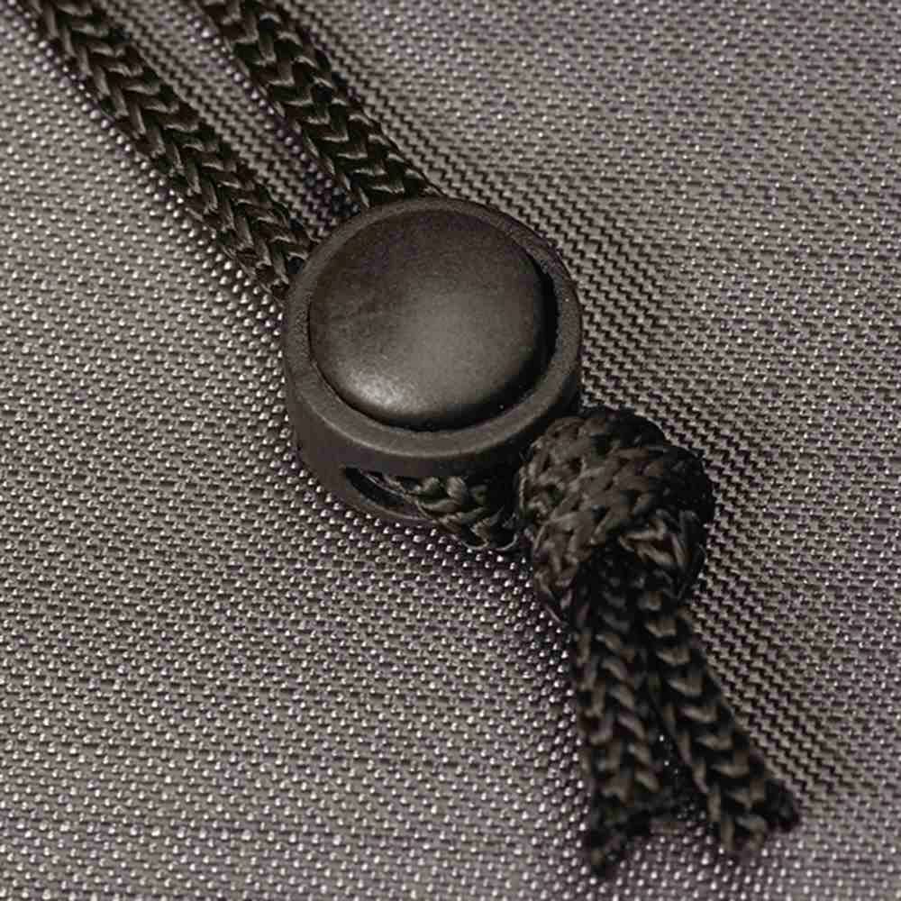 Ein schwarzer Kordelstopper auf einem grauen Stoffhintergrund. Kordel durchgezogen und festgeknotet.