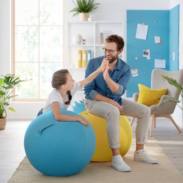 Ein Mädchen und ein Mann geben sich in einem hellen Wohnzimmer mit Pflanzen und moderner Einrichtung ein High-Five.