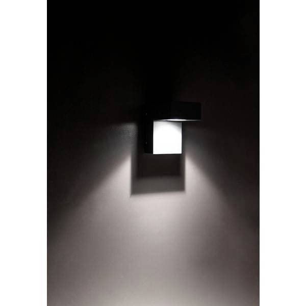 Eine moderne Wandleuchte leuchtet in einem dunklen Raum und erzeugt eine Lichtspirale an der Wand.