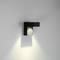 Eine moderne Wandleuchte in L-Form aus schwarzem Metall strahlt Licht nach unten und an die Wand, und erzeugt weiche Schatten.