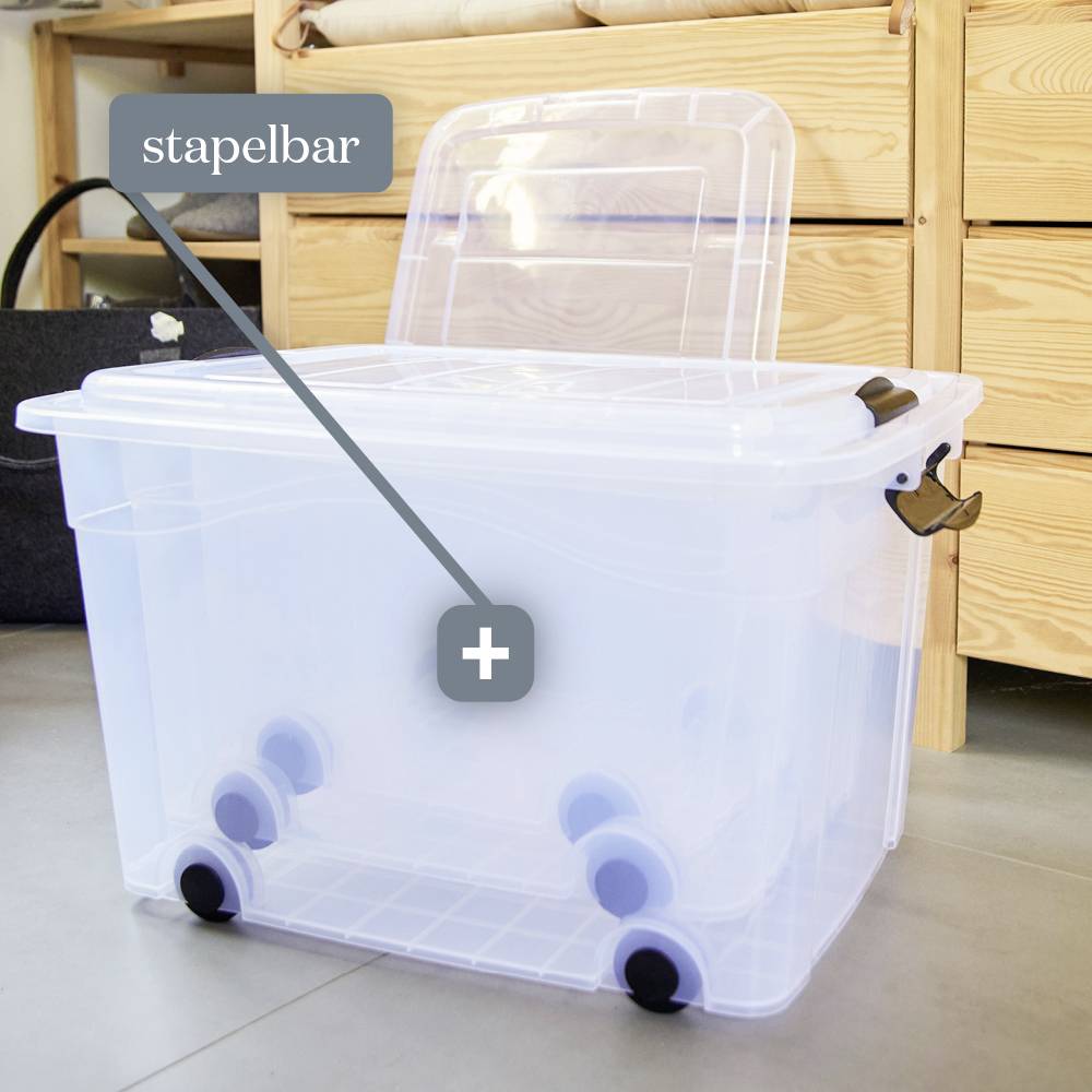Durchsichtige Aufbewahrungsbox mit Rollen und Deckel, daneben ein Etikett mit der Aufschrift 'stapelbar'. Im Hintergrund ein Holzschrank.