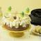 Zitronenkuchen auf gelber Tortenplatte, dekoriert mit Zitronenscheiben und kleinen Ananas-Papierdekorationsstücken.