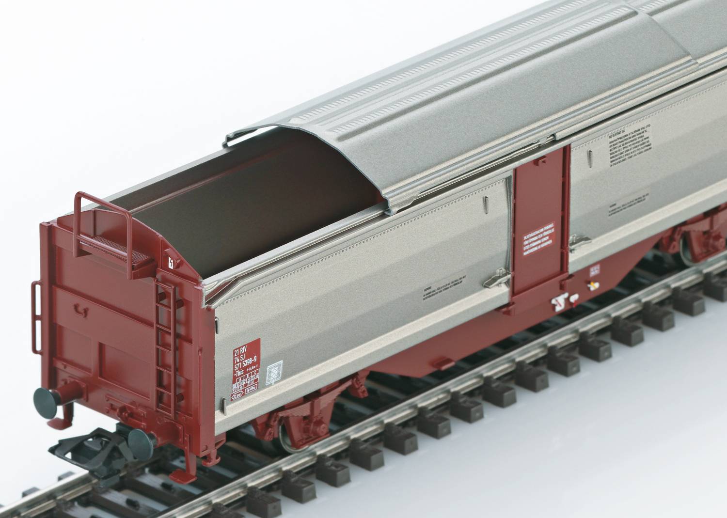 Ein grauer und roter Modell-Eisenbahn-Güterwagen mit offenem Dach auf Schienen, geeignet für den Transport von Schüttgut.