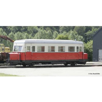 Ein historischer roter Schienenbus steht auf einem Gleis vor einem bewaldeten Hintergrund.