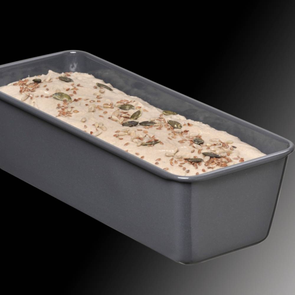 Ein Brotlaib in einer rechteckigen Backform, noch nicht gebacken. Der Teig ist mit verschiedenen Kernen bestreut.