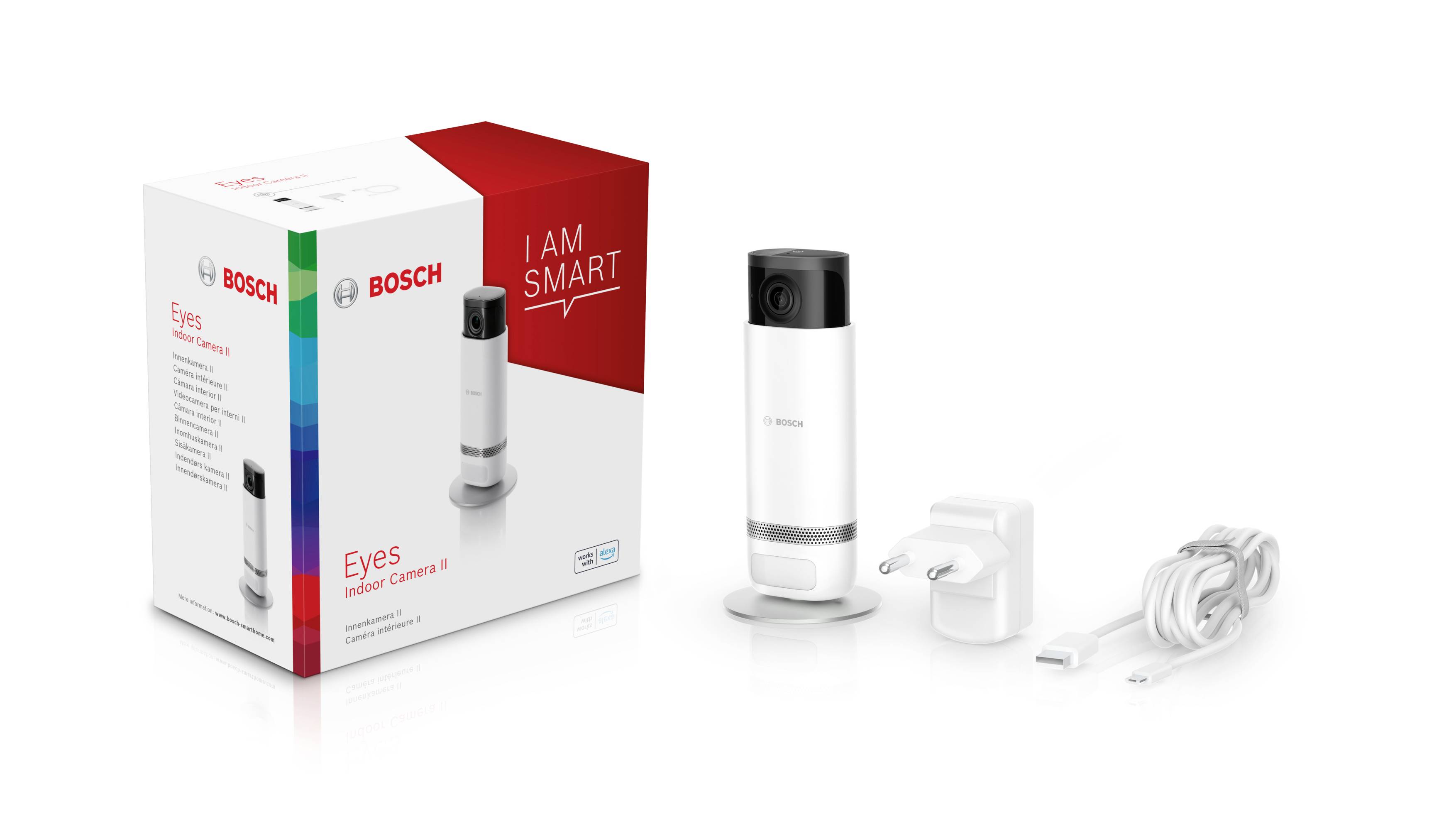Bosch Eyes Innenkamera mit weißem Gehäuse, Stromadapter und Ladekabel nebeneinander. Verpackung mit 'I Am Smart'-Aufschrift.