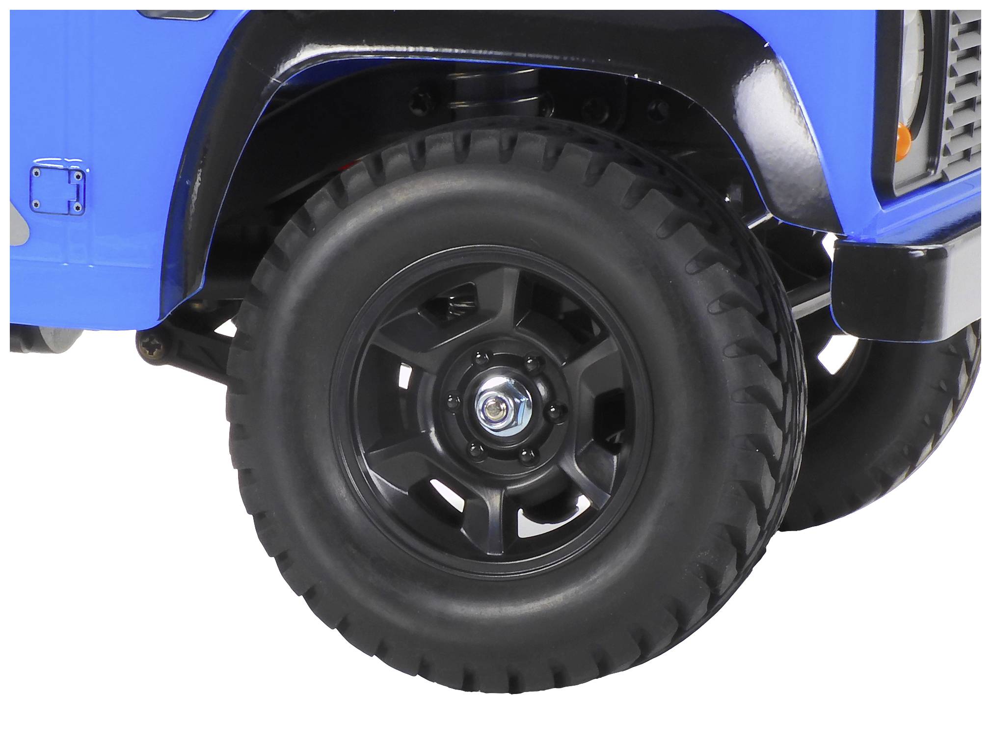 Vorderansicht eines blauen Geländewagens mit robusten schwarzen Reifen und erkennbaren Radkappen, deutet auf Offroad-Einsatz hin.