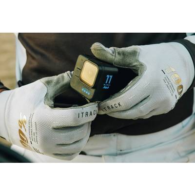 Eine Person hält eine GoPro-Kamera mit beiden Händen, bekleidet mit grauen Handschuhen. Hauptfokus: die Kamera.
