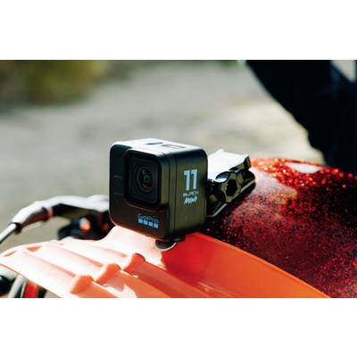 Eine GoPro-Kamera ist auf einem orangefarbenen Helm montiert. Sie befindet sich im Freien bei natürlichem Licht.