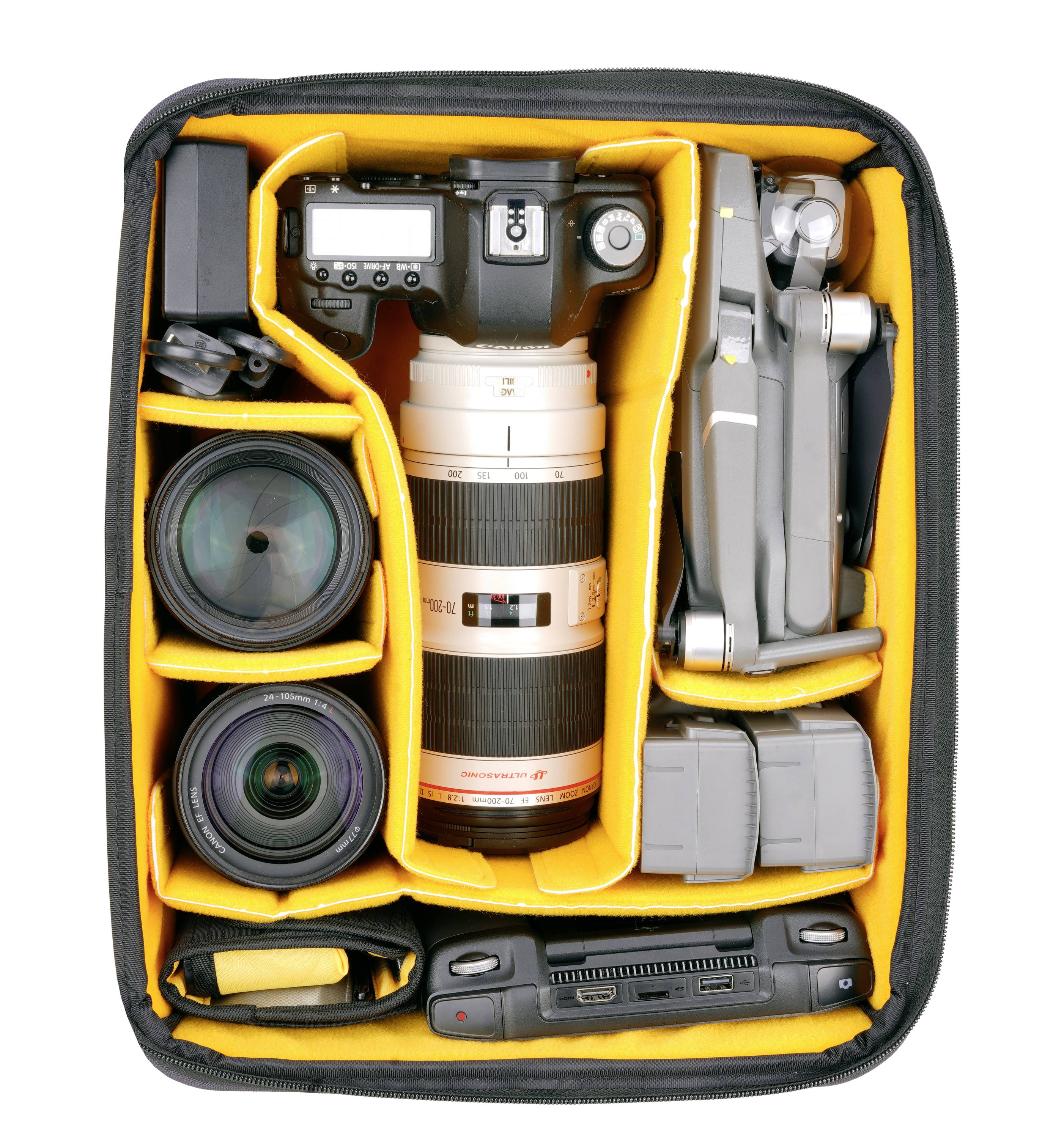 Eine Kamera mit Objektiven, Drohne, Hochformatgriff und Zubehör in einer gepolsterten Tasche organisiert.