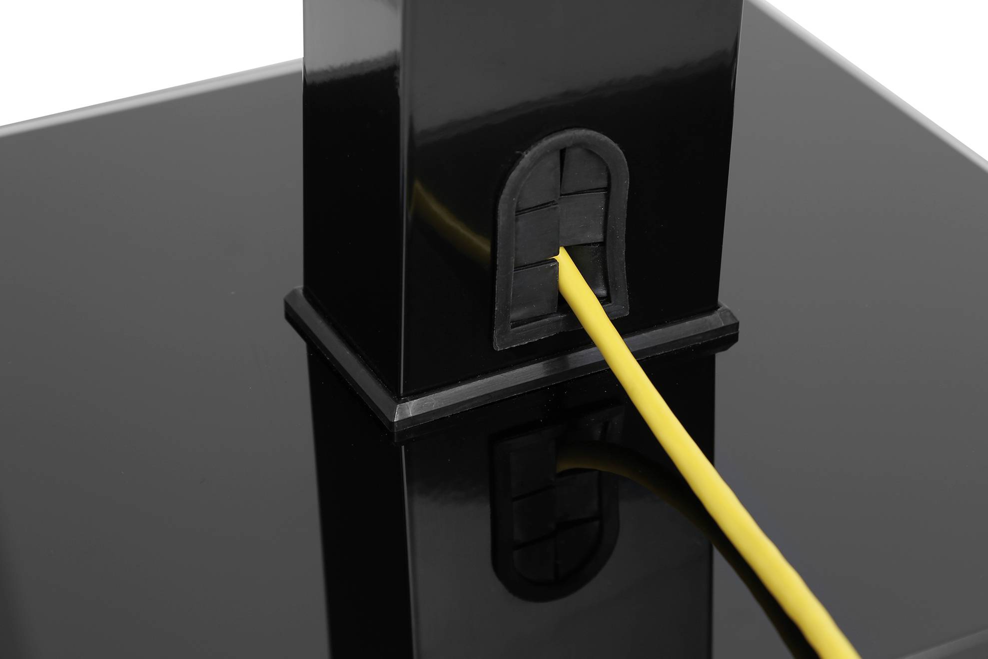 Ein gelbes Kabel ist in eine schwarze, turmartige Struktur eingesteckt, die auf einer spiegelnden Oberfläche steht.