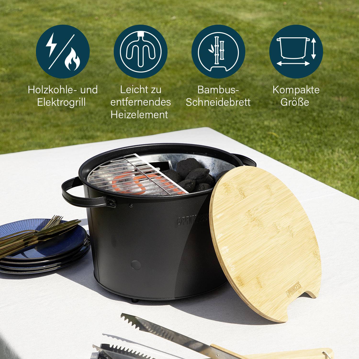 Ein Grill mit einem Holzkohle- und Elektroelement, einem Bambus-Schneidebrett und kompakter Größe auf einem Tisch im Freien.