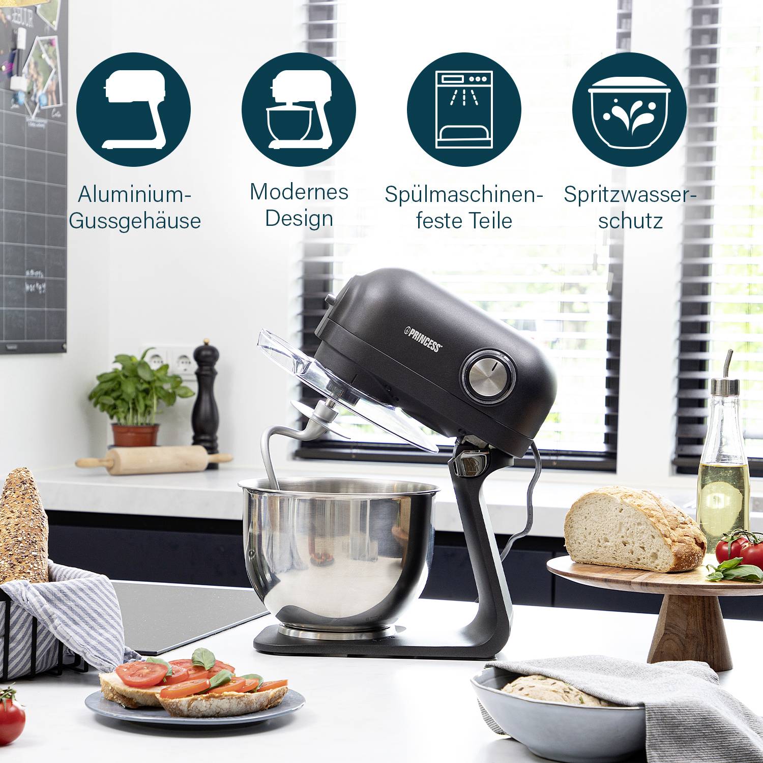 Ein moderner Küchenmixer auf einer Arbeitsplatte, umgeben von Brot, Tomaten und einer Tafel. Text beschreibt: ‚Aluminium-Gussgehäuse, modernes Design, spülmaschinenfeste Teile, Spritzwasserschutz‘.