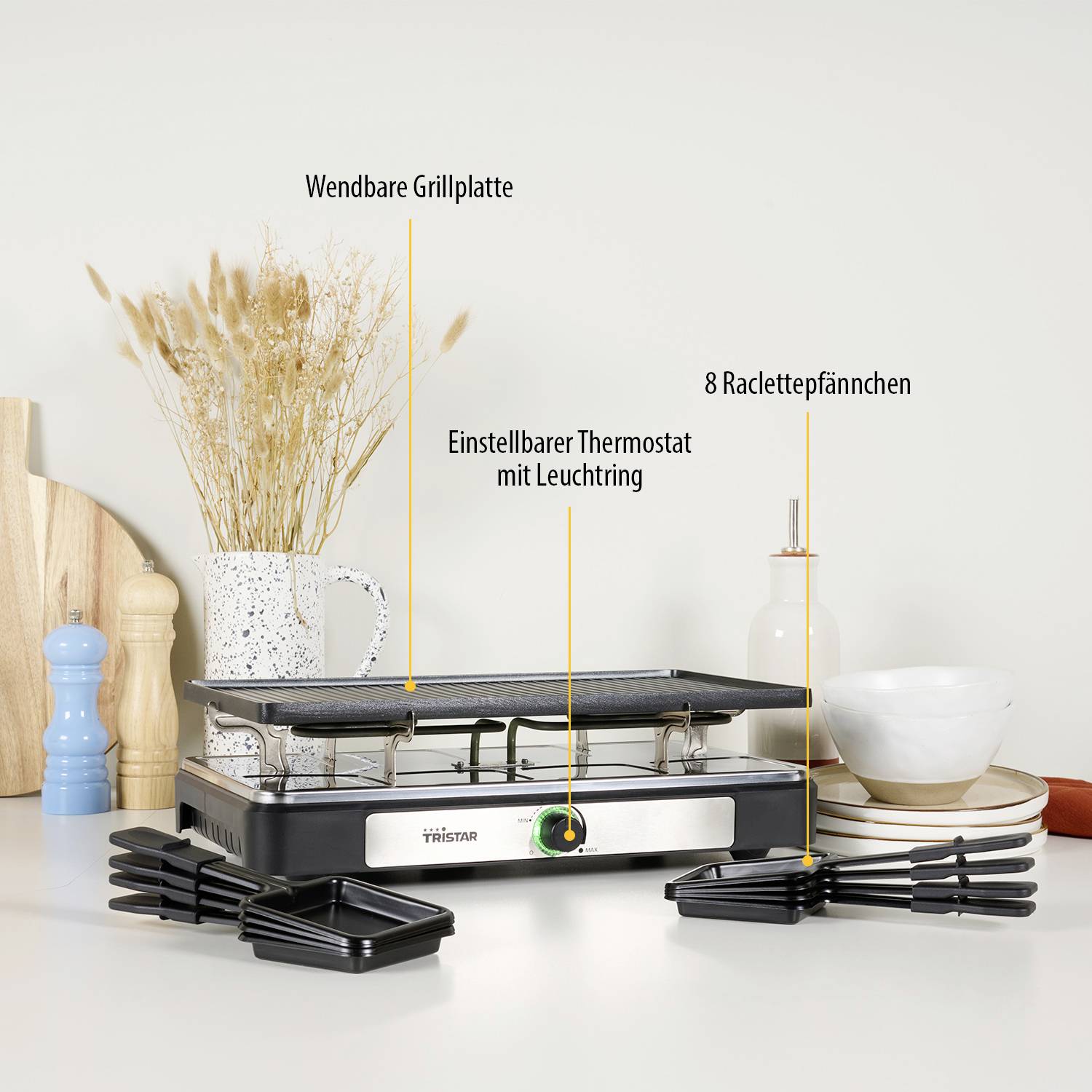 Ein Raclette-Grill mit beschrifteten Funktionen: 'Wendbare Grillplatte', 'Einstellbarer Thermostat mit Leuchtanzeige', '8 Raclettepfännchen'.