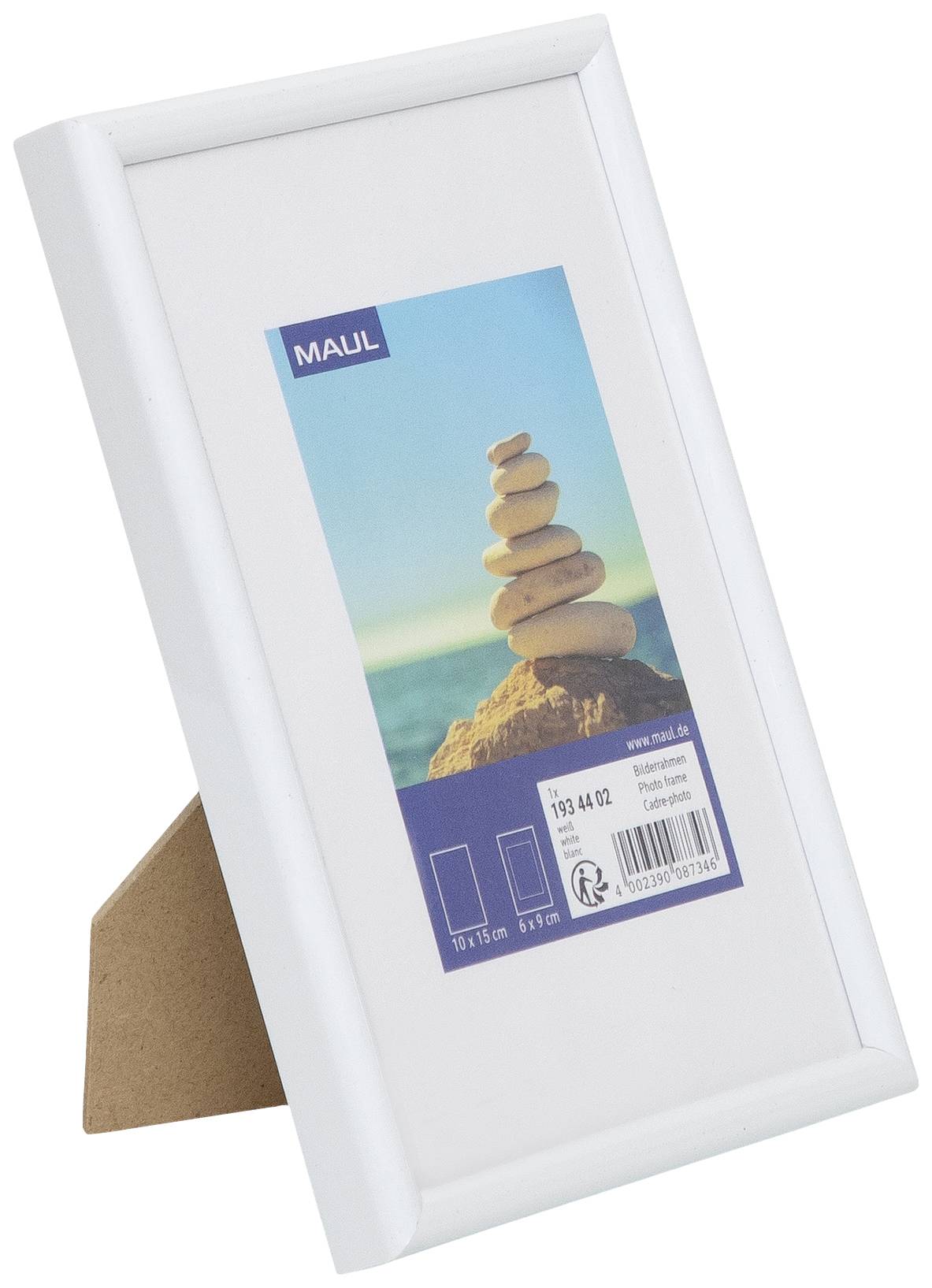 'Ein weißer Bilderrahmen mit einem Foto von gestapelten Steinen auf einem Felsen am Meer. Im Hintergrund blauer Himmel und Wasser.'