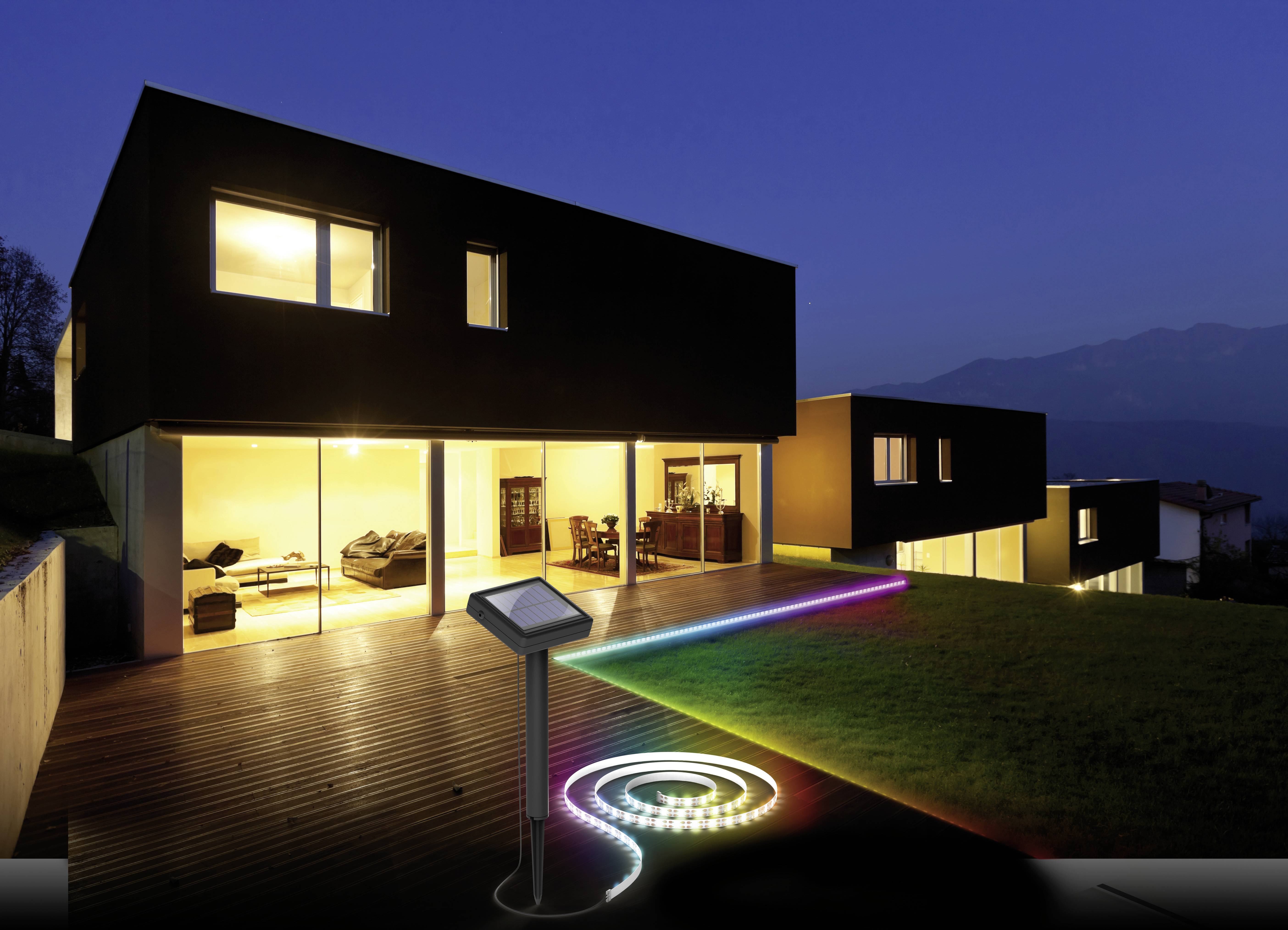 Zwei moderne, minimalistische Häuser bei Dämmerung. Der Garten ist mit bunten LED-Leuchten verziert, die einen Pfad beleuchten.