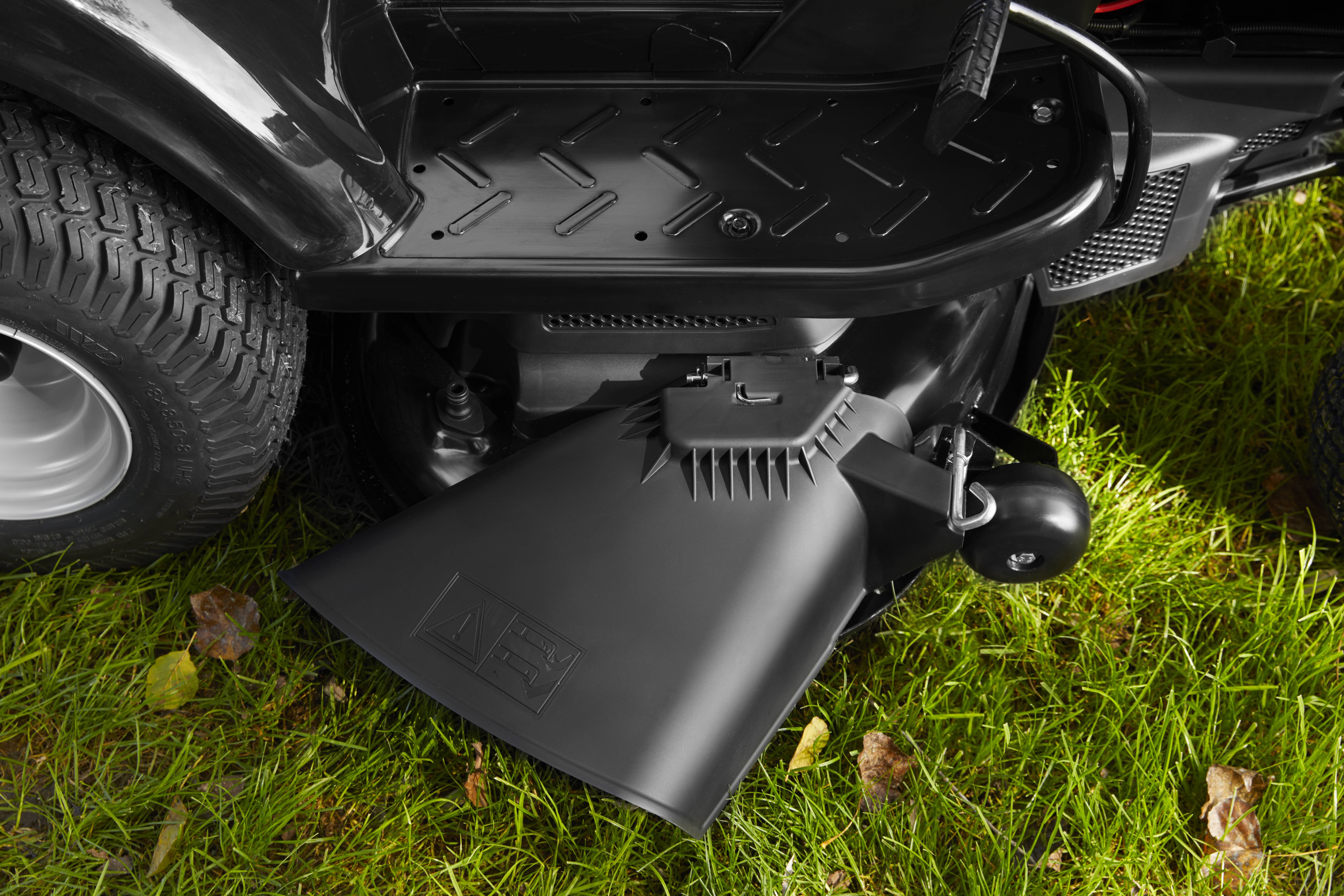 Nahaufnahme eines schwarzen Rasenmäherauswurfs mit Rasenhintergrund.