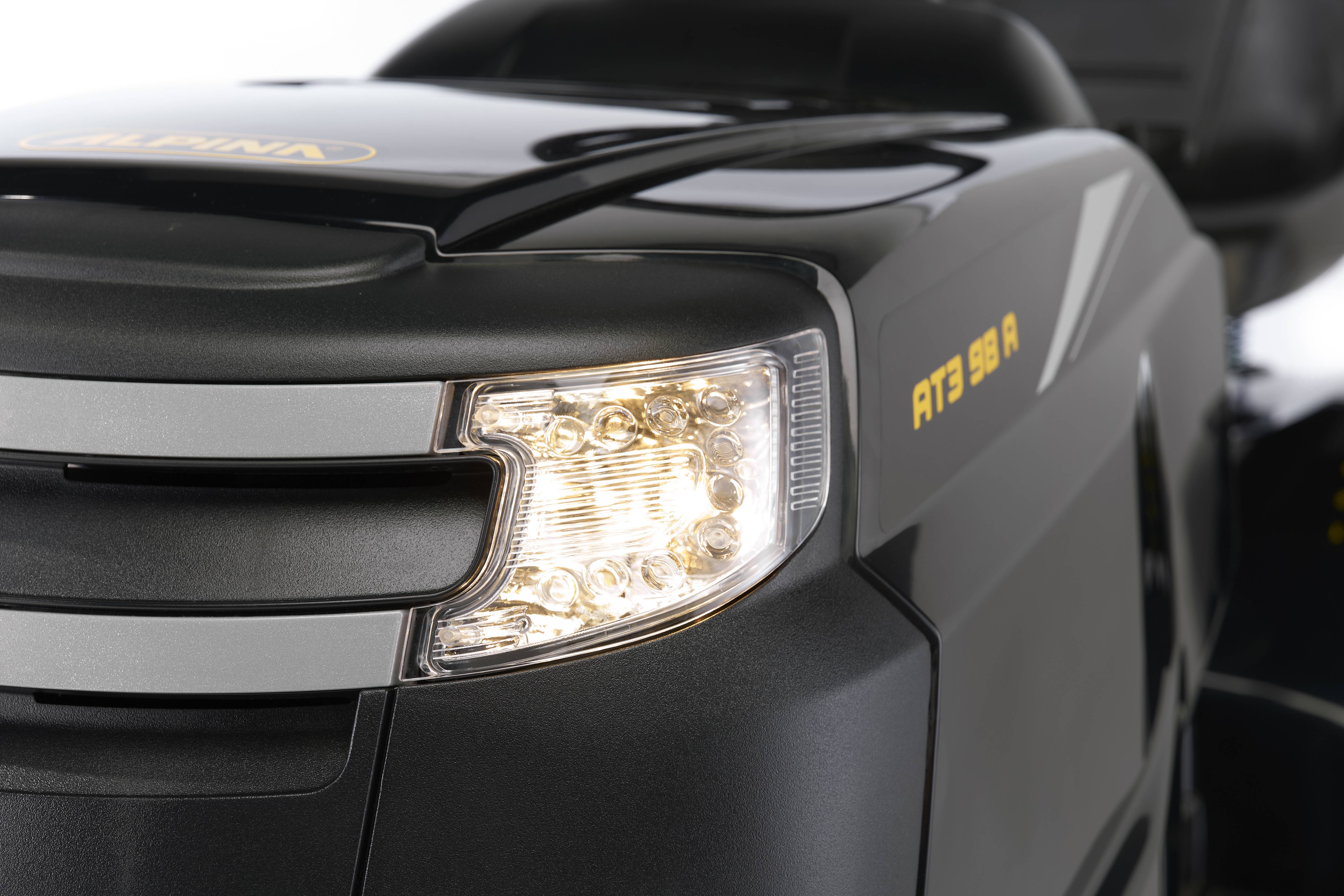 Rasenmäher mit Frontscheinwerfer und dem Modellnamen 'AT3 98 A' an der Seite. Modernes Design, glänzende schwarze Oberfläche.