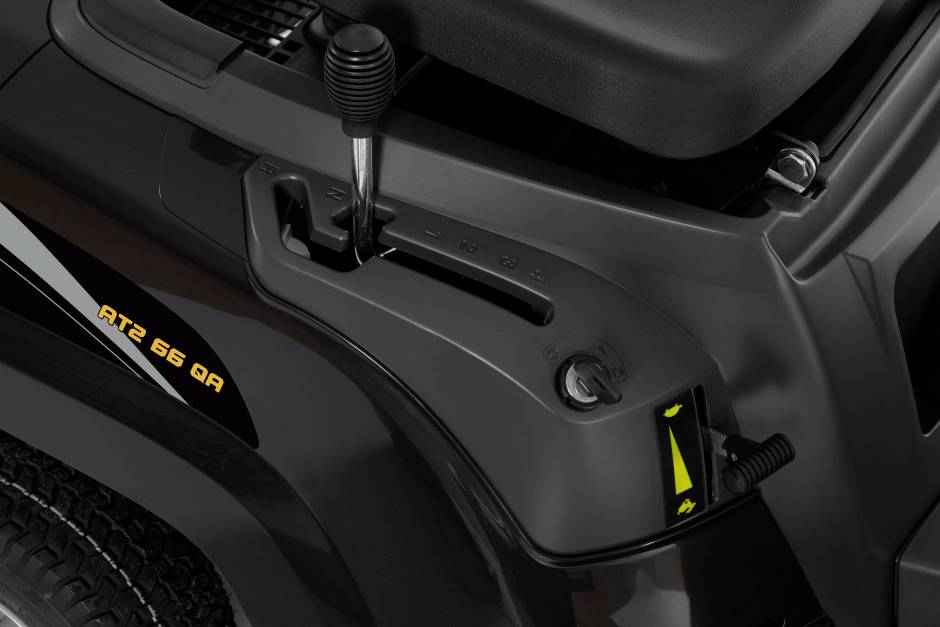 Ein schwarzes Cockpit mit Schalthebel und Hebel für die Geschwindigkeitsregelung eines Rasenmähers. Links die Aufschrift 'ATZ 66 QA'.