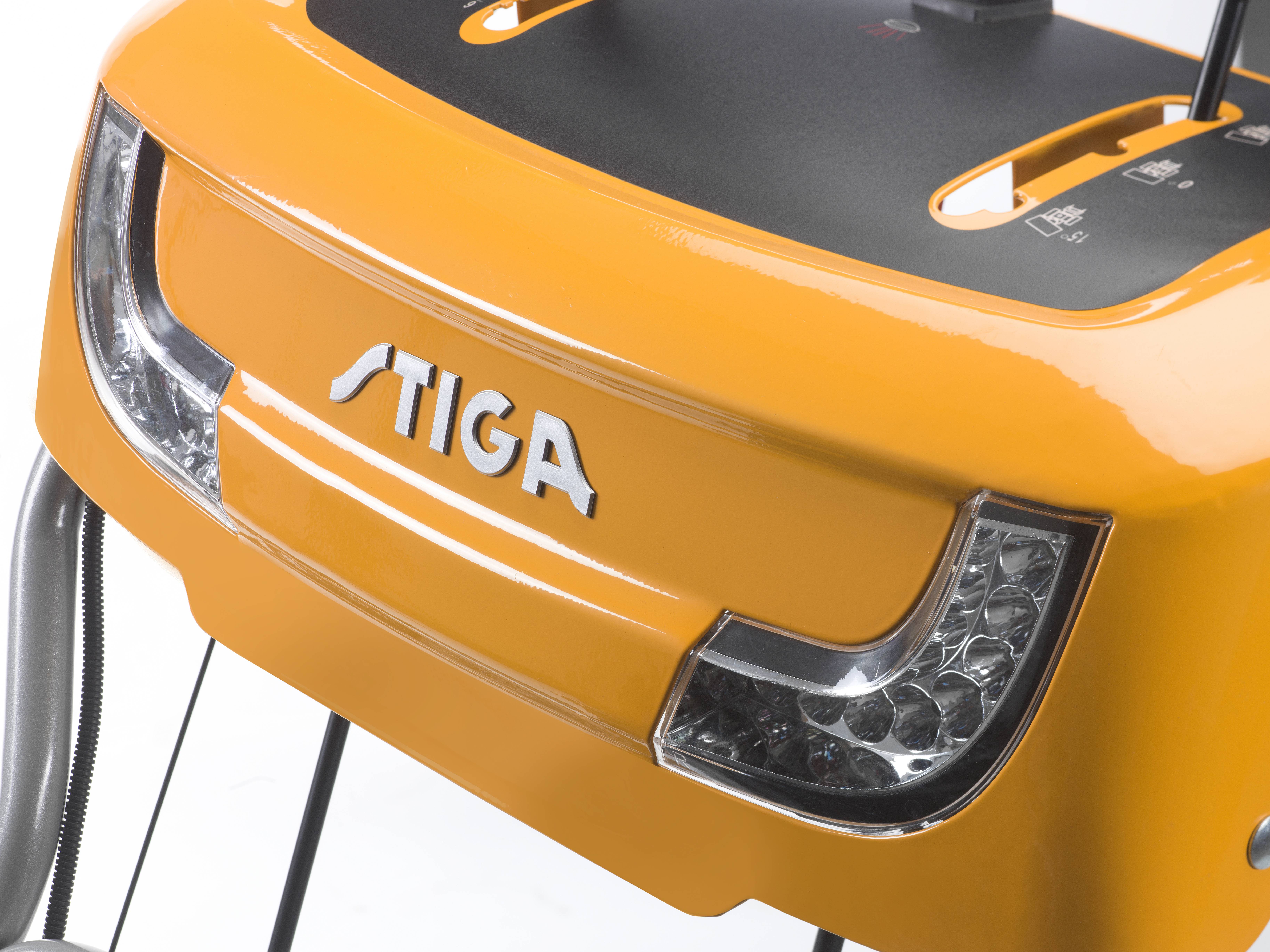 Ein gelbes Gerät mit dem Logo 'STIGA' zeigt einen Teil eines Rasenmäher-Tisches. Markantes Design mit LED-Leuchten.