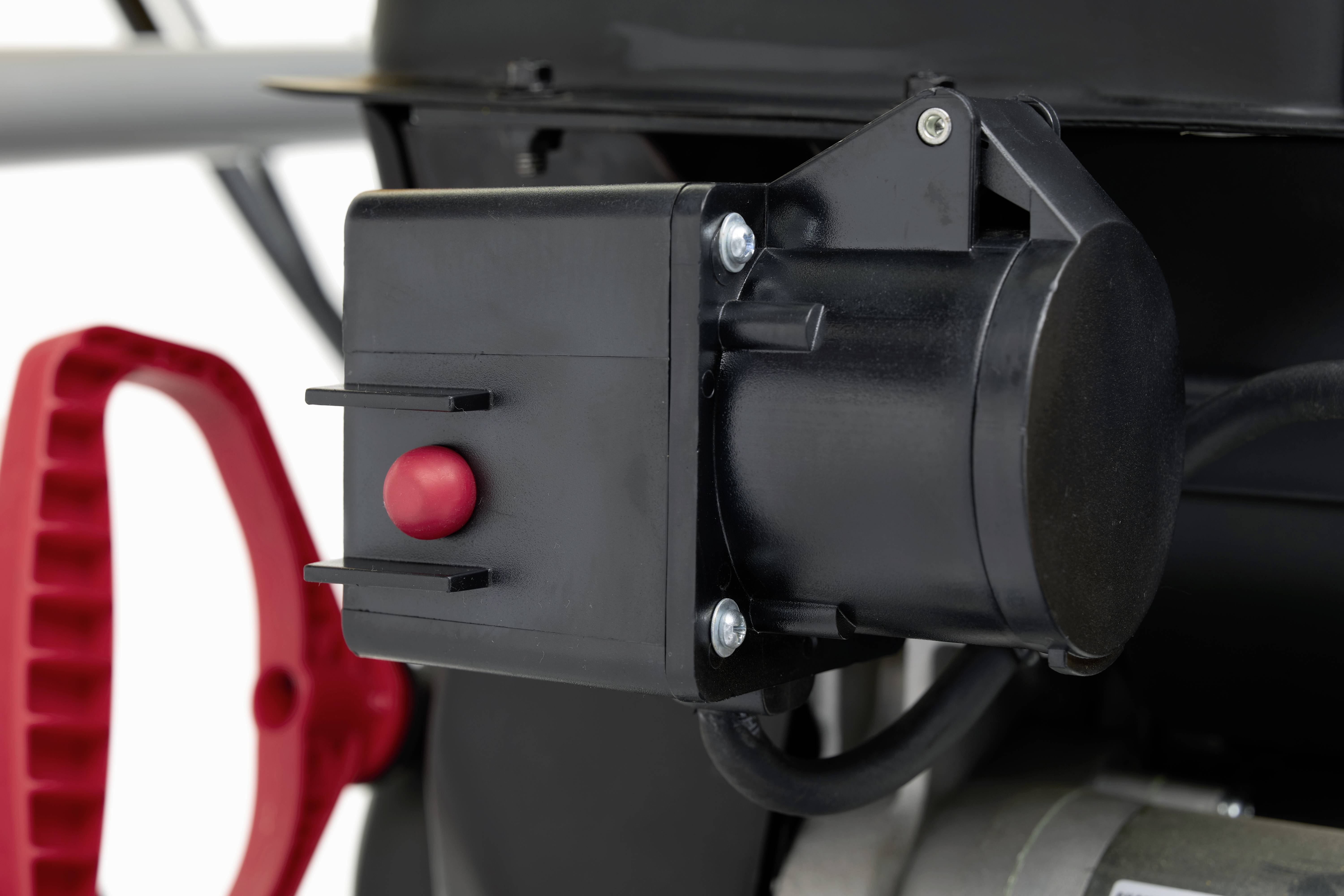 Detailaufnahme eines Maschinenmotors mit rotem Knopf im Vordergrund, möglicherweise zum Starten oder für eine andere Funktion.