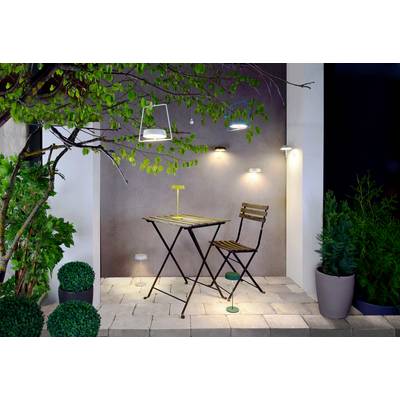 Ein kleiner Terrassenbereich mit einem Tisch, einem Stuhl und moderner Beleuchtung ist von Pflanzen umgeben und wirkt gemütlich und einladend.