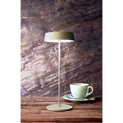 Eine moderne Tischlampe steht auf einem Holztisch neben einer mintgrünen Tasse und Untertasse, vor einem dunklen, strukturierten Hintergrund.