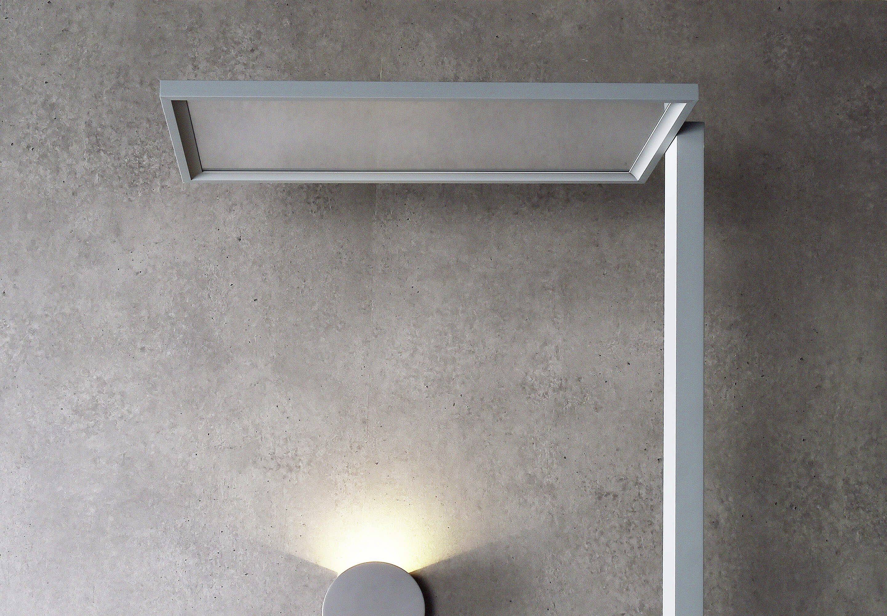 Eine moderne, minimalistische Wandleuchte mit rechteckigem Schirm, strahlt Licht nach unten auf eine graue Betonwand.