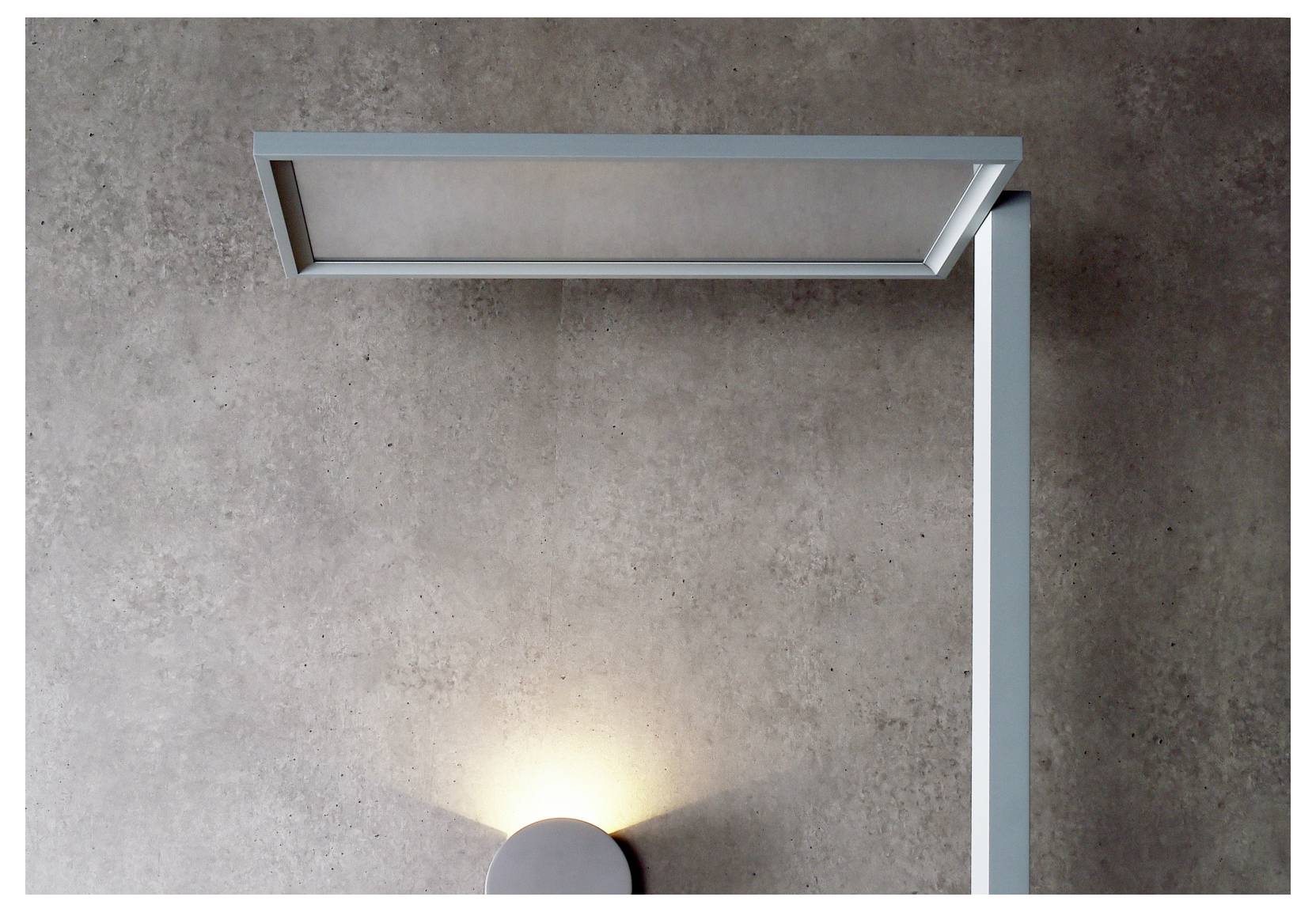 Minimalistische moderne Wandleuchte mit einem langen, horizontalen Lichtbalken an einer senkrechten Halterung, die eine sanfte Lichtstimmung auf eine Wand mit Betonoptik wirft.