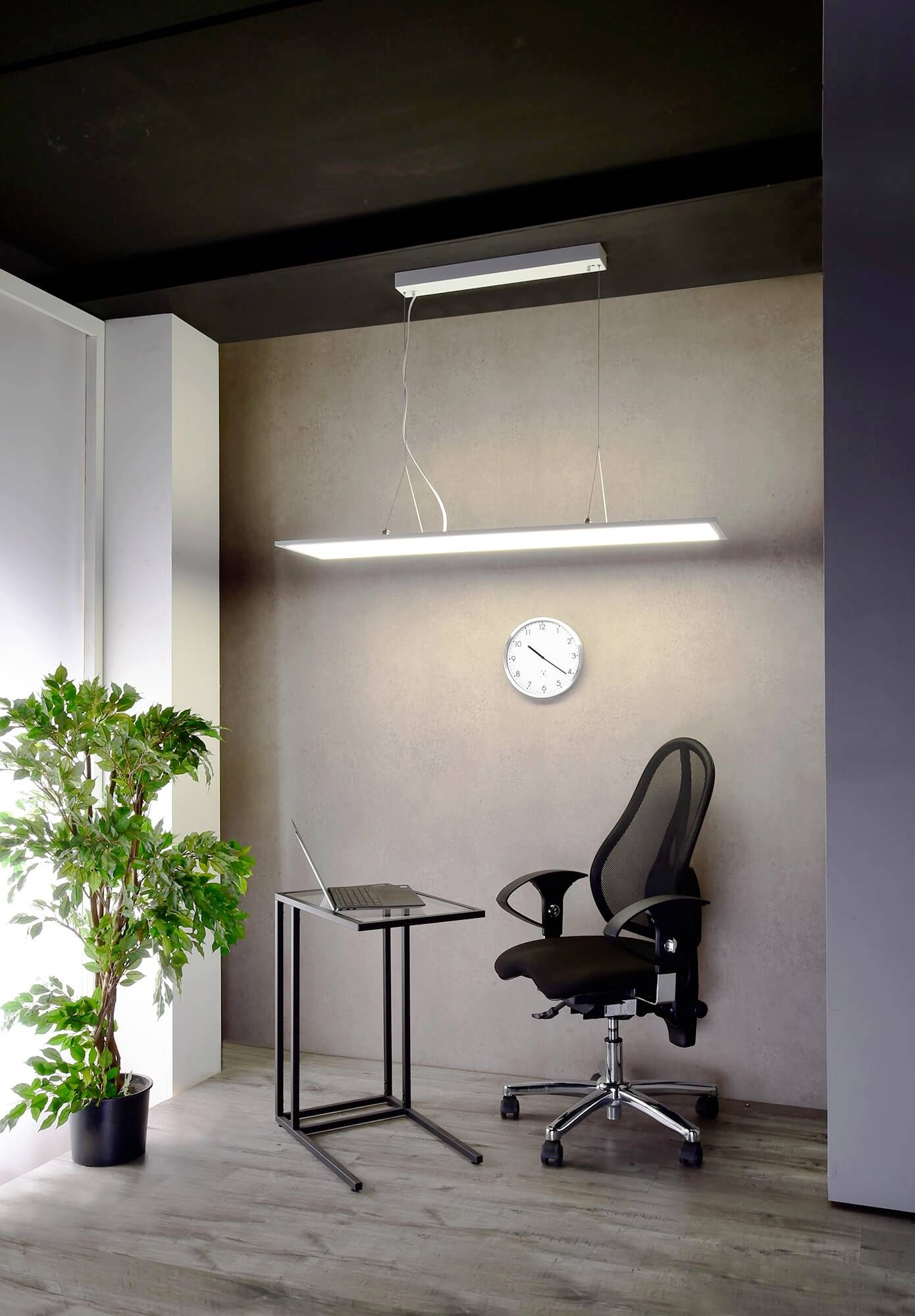 Ein minimalistisches Arbeitszimmer mit modernem Schreibtischstuhl, kleinem Tisch mit Laptop, Wanduhr und einer Pflanze in der Ecke.